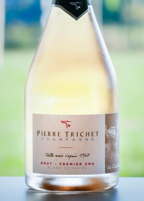 Bouteille de champagne Pierre Trichet Brut Blanc de Noirs Premier Cru posé sur une table